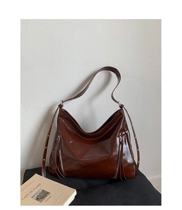 Detailed view of dark brown glossy patent leather shoulder bag with silver zippers