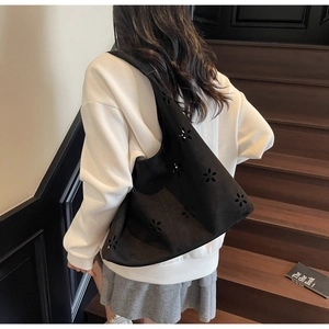 Détail d'un sac cabas noir avec motifs floraux découpés au laser et une bandoulière chic