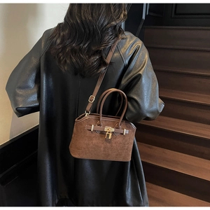 Détail du sac vintage marron foncé en daim avec fermoir doré et bandoulière élégante