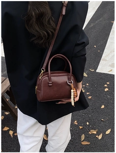 Vue arrière d'un sac bandoulière vintage en similicuir marron foncé porté en extérieur