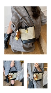 Chic beige canvas bucket bag with black leather trim and cute bear charm shown on model
