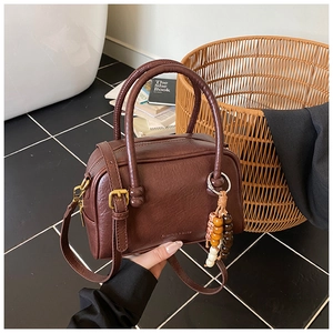Détail d'un sac Boston vintage marron avec texture litchi et breloque en perles