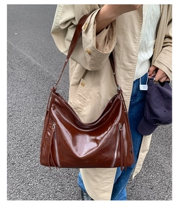 Detail of glossy brown patent leather tote with vertical zippers and long tassels