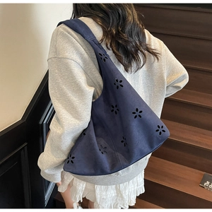 Détail du motif floral découpé au laser sur le sac à bandoulière en daim bleu foncé