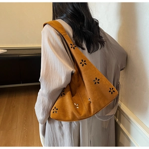 Sac à épaule en daim marron avec motifs floraux découpés au laser porté par un mannequin