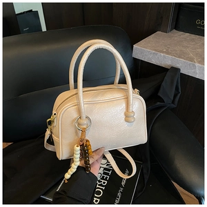 Détail du sac à main crème avec pampille en perles et texture en cuir lisse élégante