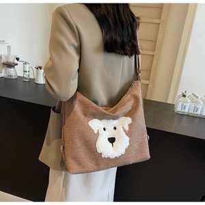 Brown canvas crossbody bag with plush dog patch shown in a casual lifestyle setting