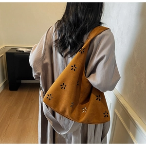 Sac hobo en daim marron avec fleurs découpées au laser porté à l'épaule du mannequin
