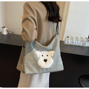 Detailed view of grey fabric tote bag featuring a cute 3D plush dog on the shoulder