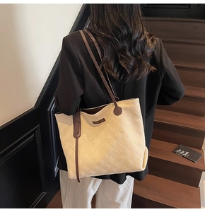 Detail view of cream canvas tote bag featuring quilted diamond pattern and brown straps