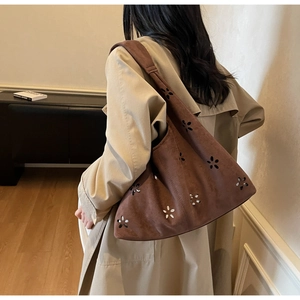 Détail du sac à bandoulière marron ajouré porté par un mannequin dans un salon épuré