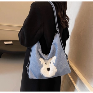 Detail view of denim texture and schnauzer dog patch embroidery on light blue tote bag