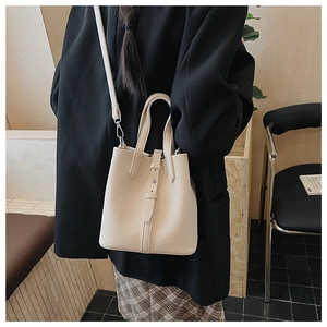 Detailed view of a creamy white lychee pattern leather bucket bag with silver metal rivets