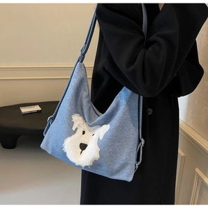 Detail of blue denim shoulder bag with a fluffy white dog applique and adjustable strap