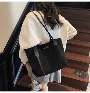 Rear view of a model carrying a black quilted tote bag with thin shoulder straps