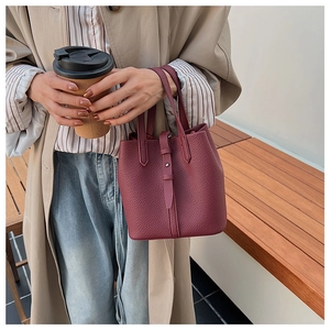 Detailed close-up of burgundy lychee grain leather bucket bag with buckle closure