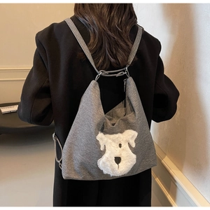Detail of grey soft fabric shoulder bag with cute white plush dog patch design