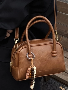Sac Boston marron vintage avec boucle dorée et breloque perlée porté à l'épaule
