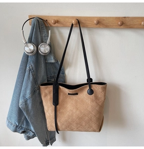 Detail of khaki quilted suede tote bag with slim black straps and a minimalist label
