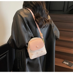 Détail d'un sac bandoulière chic rose et beige avec motifs cerfs et fermoir métal