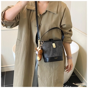 Detail view of stylish bucket bag with golden buckle and cute plush bear accessory