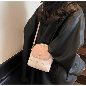 Détail du sac bandoulière rose et blanc avec texte FASHION sur modèle en manteau de cuir noir