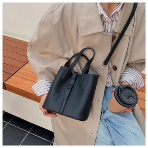 Close-up of black lychee grain leather bucket bag with silver buckle and crossbody strap