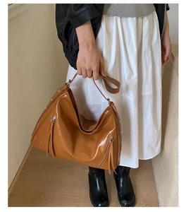 Caramel brown leather tote bag with vertical zipper details and wide shoulder strap