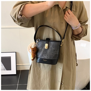 Detail of black and marble bucket bag with gold clasp and brown teddy bear charm
