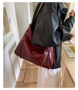 Detail of burgundy tote bag featuring stylish zipper tassels and premium faux leather finish