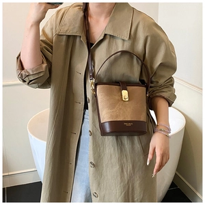 Detail of a color-block bucket bag with matte brown texture and elegant golden metal twist lock