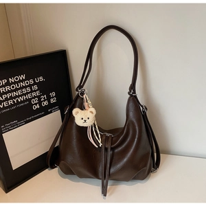 Detail of dark brown PU leather hobo bag with cute plush bear and ribbon decoration
