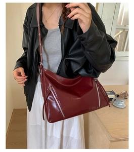 Detail of burgundy large tote bag with silver zippers shown in a lifestyle indoor setting
