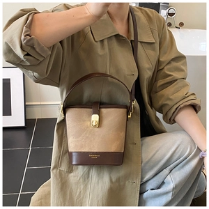 Detail view of khaki and brown bucket bag with gold lock and textured material