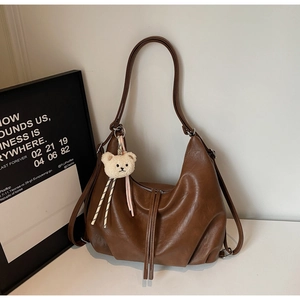 Detail view of brown hobo bag with soft leather texture and cute plush bear charm