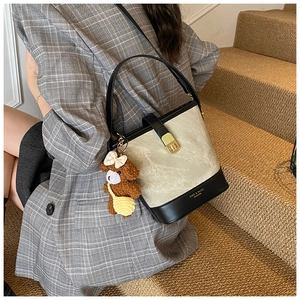 Detail of canvas bucket bag with black leather trim and cute brown teddy bear charm