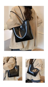 Detail van de glanzende zwarte tote bag met metalen sluiting en slanke schouderbanden voor
