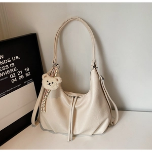Detail of cream white large tote bag with plush bear charm and soft pleated leather