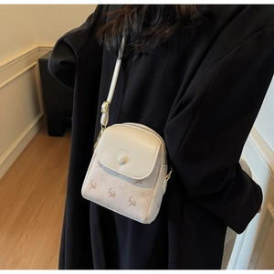 Détail du mini sac bandoulière en cuir PU à motif cerf porté sur un élégant manteau noir