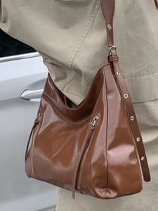 Brown glossy patent leather hobo tote bag with metal eyelets and side zippers