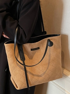Brown suede tote bag with diamond quilting and slim straps worn by a model in soft light