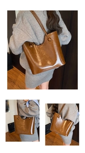Detailweergave van grote bruine tote bag met glanzend leer en een ronde gesp erop