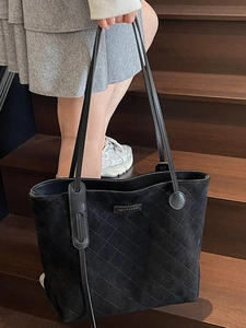Elegant black quilted tote bag with thin straps and metal logo for chic daily commuting