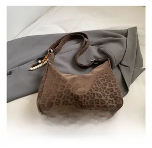 Detailed macro view of brown leopard print suede bag with wooden bead tassel charm