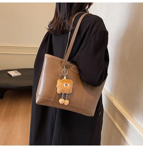 Détail du grand sac cabas en cuir marron avec bandoulière et pendentif en peluche