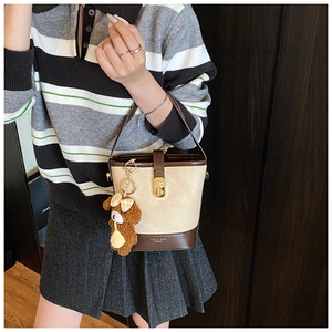 Detailed side view of vintage beige bucket bag with brown trim and cute bear charm