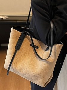 Beige quilted tote bag with black leather straps and elegant diamond pattern