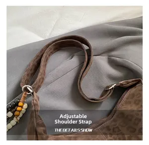 Detail of adjustable leopard print strap with retro beads on brown suede tote bag