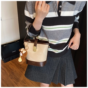 Detail view of a beige bucket bag with gold twist lock and a cute plush bear pendant