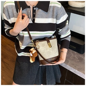 Detail of vintage bucket bag with contrast leather trim and cute brown bear charm